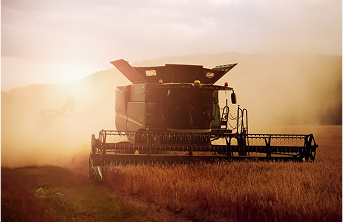 Una cosechadora trabajando en un campo al atardecer